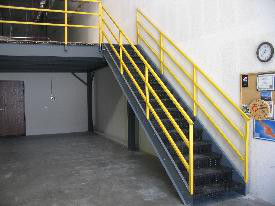 Metal stairs with yellow railing, in a warehouse