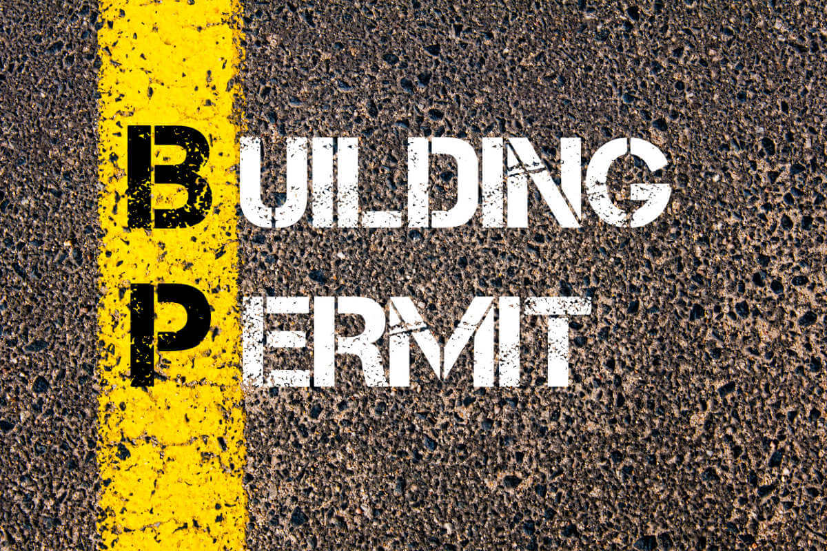 Rolled Up Plans and Diagrams on Table with Words 'Building Permit' Displayed