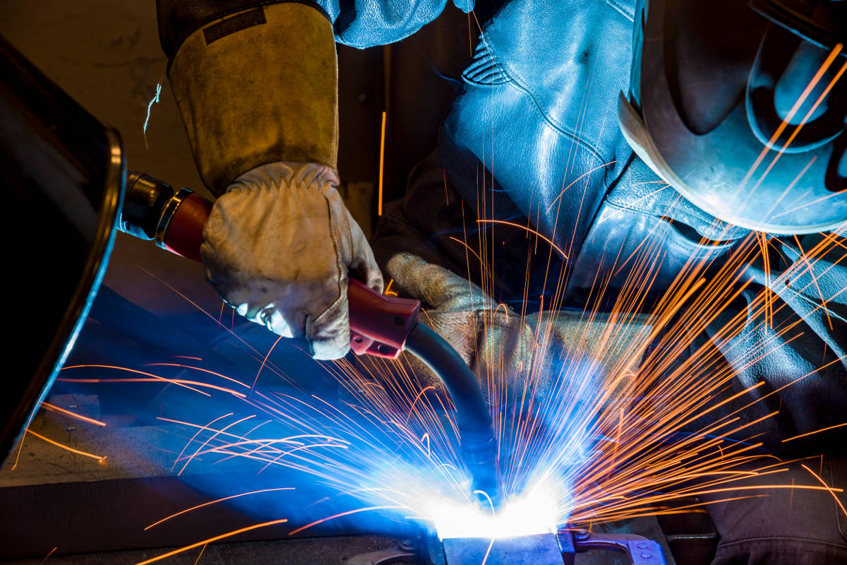 Welder Wearing Mask and Protective Clothing with Sparks Flying