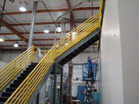 Metal stairs with yellow railing, in a warehouse